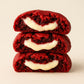 Stack of red velvet cookies with cream cheese filling on a beige background